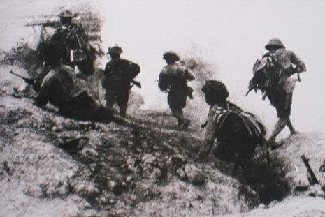 Viet Minh soldiers advancing up a dirt slope.